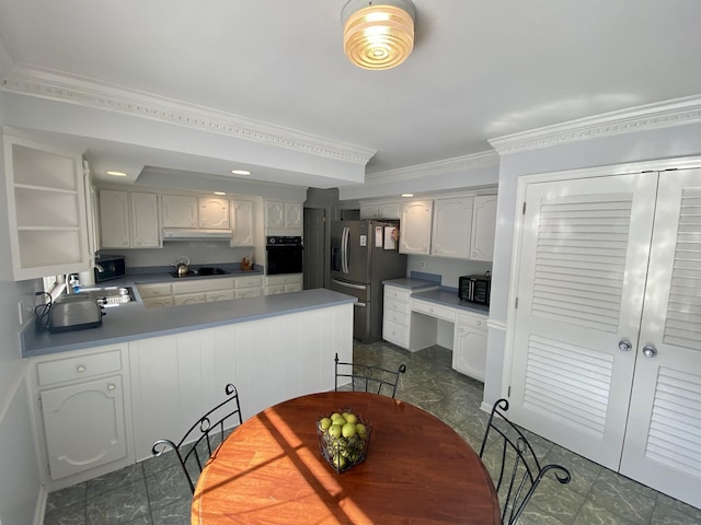 kitchen with built in desk, white cabinets, a peninsula, under cabinet range hood, and black appliances