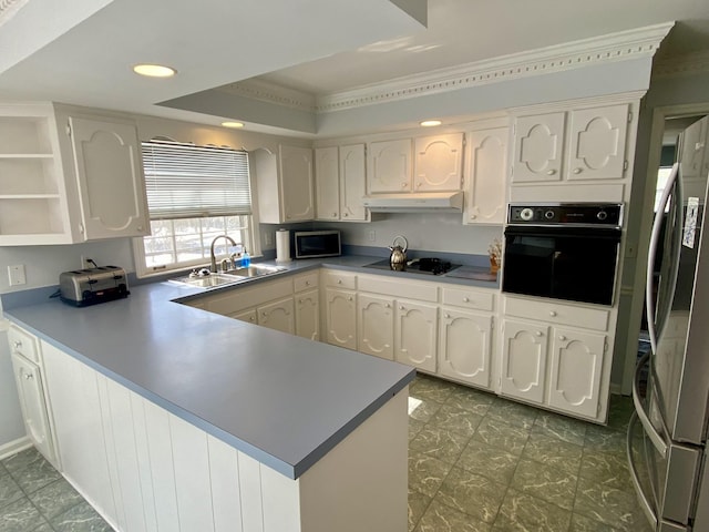 kitchen with black appliances, a peninsula, a sink, and white cabinetry