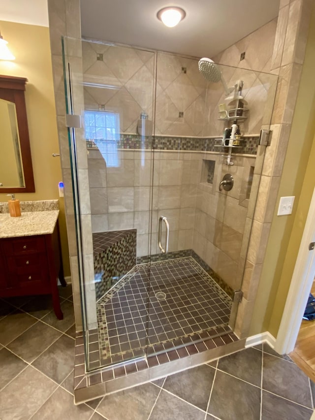 full bathroom featuring a shower stall, vanity, baseboards, and tile patterned floors