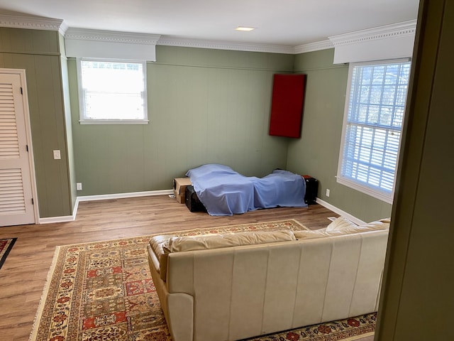 bedroom featuring ornamental molding, multiple windows, and wood finished floors