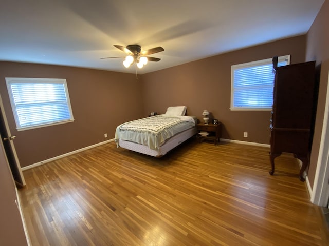 bedroom with a ceiling fan, baseboards, and wood finished floors