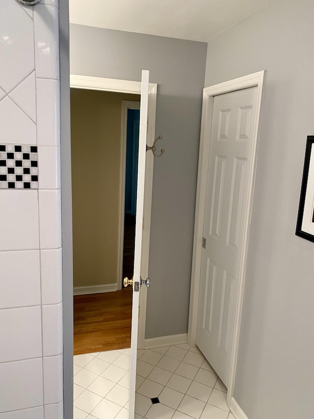 corridor with light tile patterned flooring and baseboards