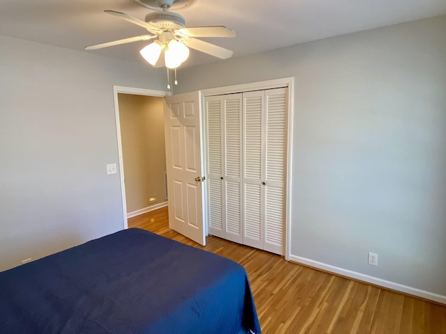 unfurnished bedroom with a closet, ceiling fan, baseboards, and wood finished floors