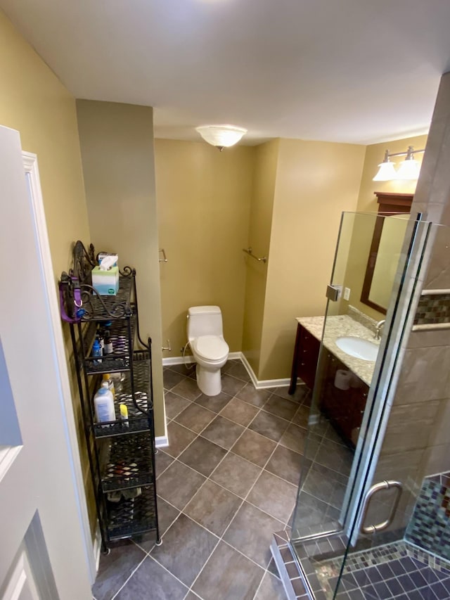 bathroom featuring toilet, a stall shower, vanity, tile patterned flooring, and baseboards