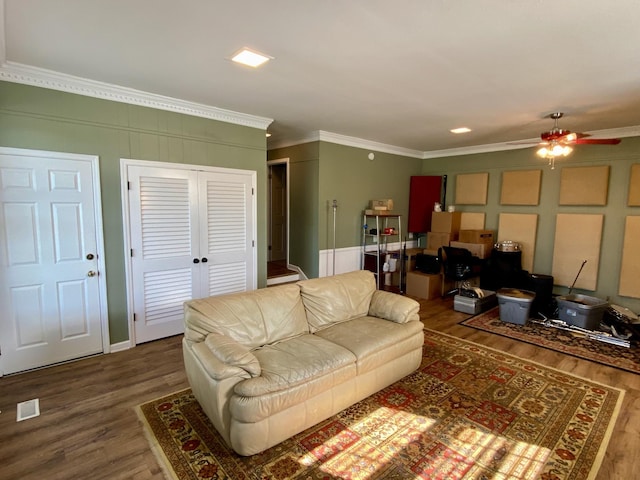 living room with ornamental molding, visible vents, a decorative wall, and wood finished floors