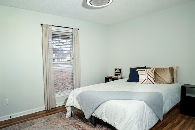 bedroom with dark wood-style flooring, a textured ceiling, and baseboards