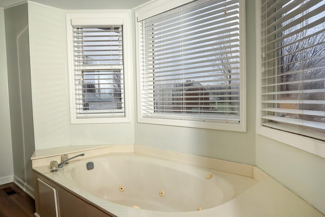 full bath with a whirlpool tub, plenty of natural light, and visible vents