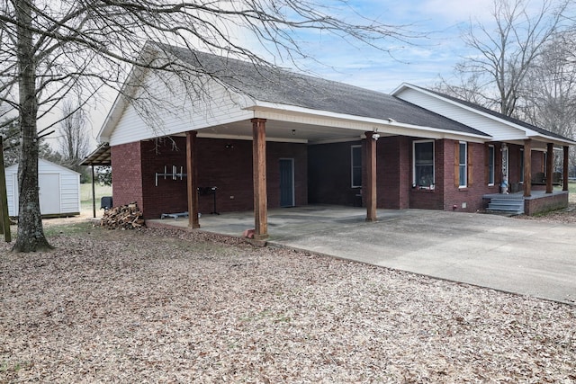 view of side of home with driveway, a storage shed, an outbuilding, and brick siding