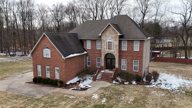 view of front of home featuring a shingled roof, stone siding, cooling unit, french doors, and brick siding