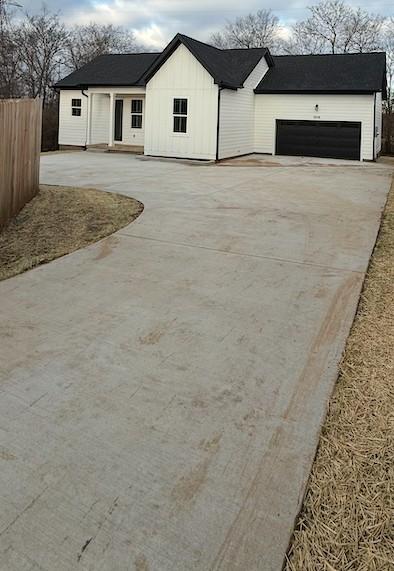 view of front of house with a garage, concrete driveway, and fence