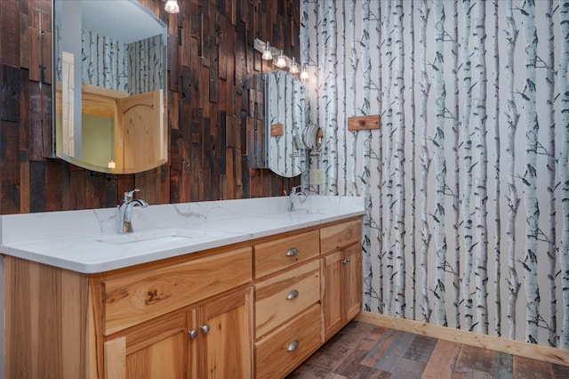 bathroom featuring double vanity, wood finished floors, and a sink