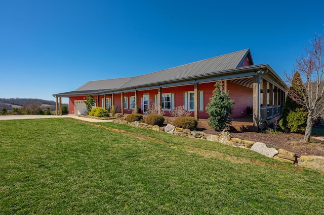 view of front of house with metal roof, a garage, covered porch, concrete driveway, and a front yard