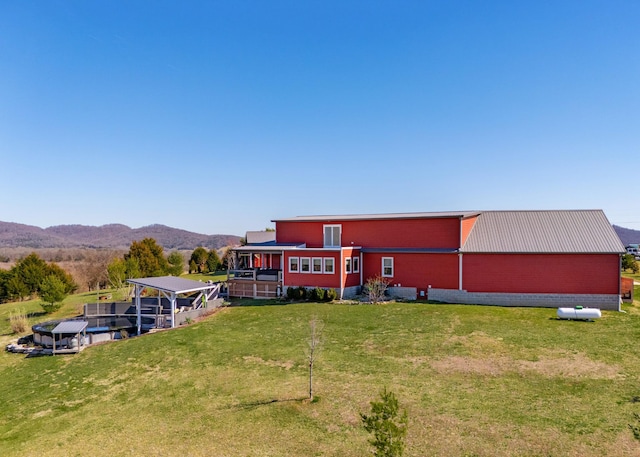 exterior space with an outbuilding, metal roof, a lawn, and a mountain view