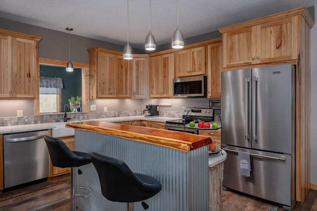 kitchen with dark wood finished floors, appliances with stainless steel finishes, a kitchen breakfast bar, hanging light fixtures, and a textured ceiling