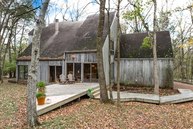 exterior space featuring roof with shingles, a chimney, and a wooden deck