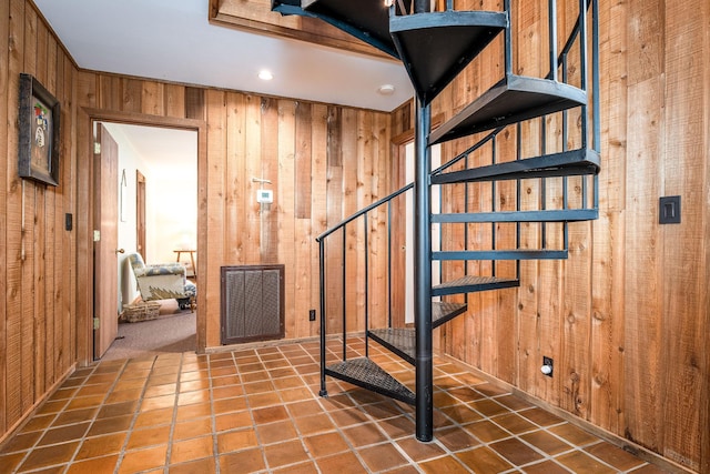 stairs featuring tile patterned flooring, visible vents, and wooden walls