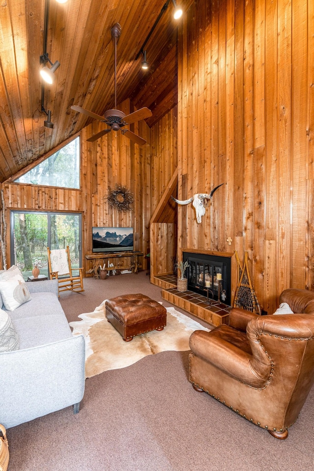 carpeted living room with high vaulted ceiling, wooden ceiling, wood walls, a fireplace, and rail lighting