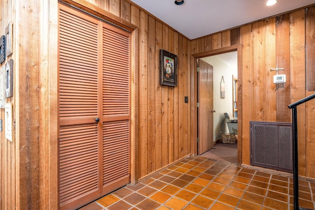 hall featuring wooden walls and dark tile patterned flooring