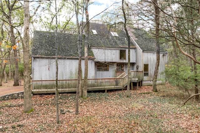 rear view of house with a deck and a shingled roof