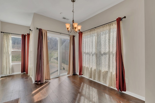 unfurnished dining area featuring baseboards, a notable chandelier, visible vents, and dark wood-type flooring