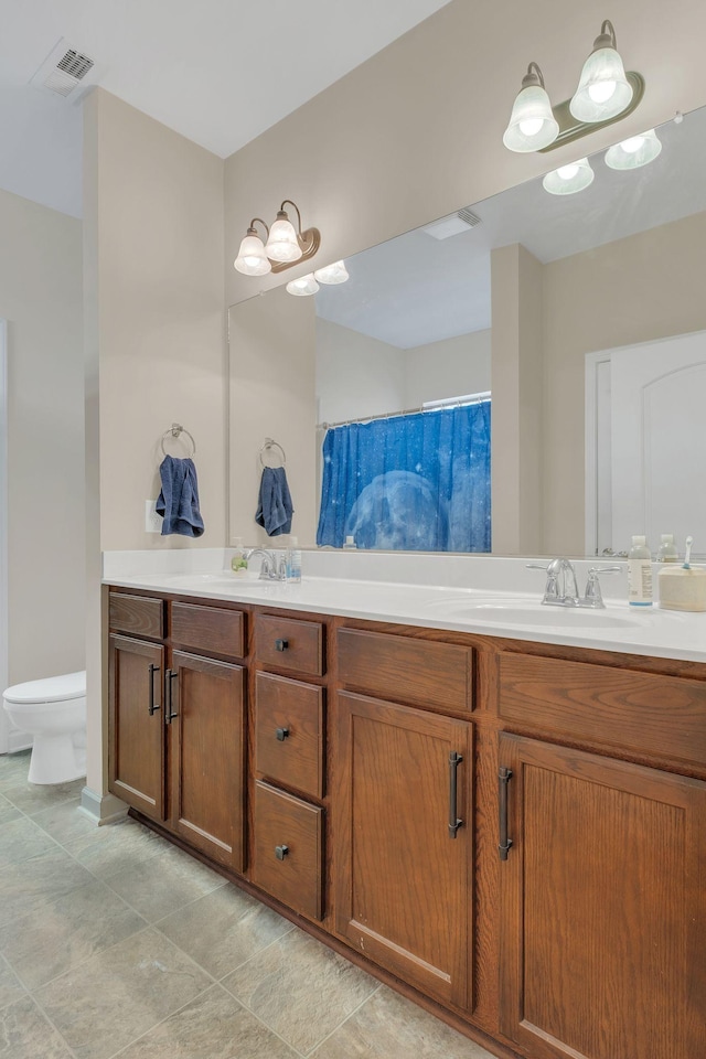 full bath with visible vents, a sink, toilet, and double vanity