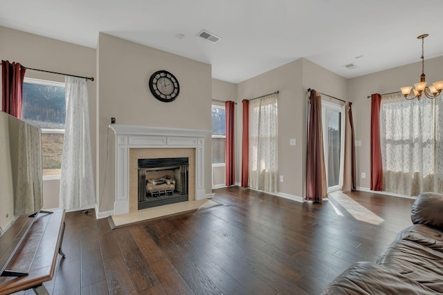 unfurnished living room with a chandelier, dark wood-style flooring, a healthy amount of sunlight, and a fireplace