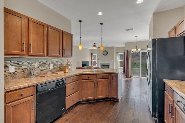 kitchen with pendant lighting, backsplash, a sink, a peninsula, and black appliances