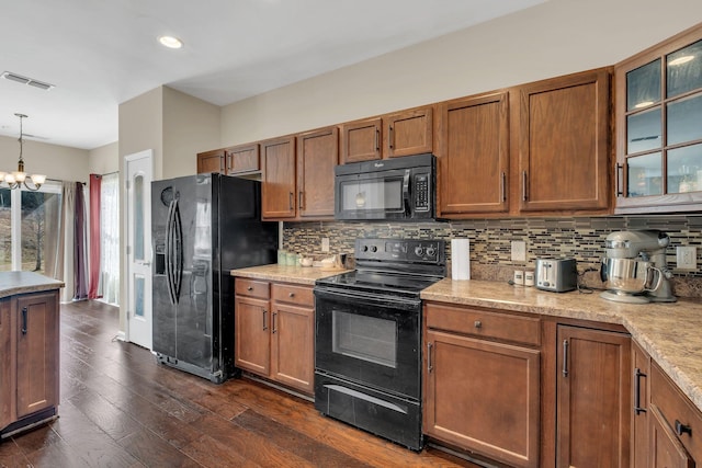 kitchen featuring visible vents, black appliances, tasteful backsplash, glass insert cabinets, and pendant lighting