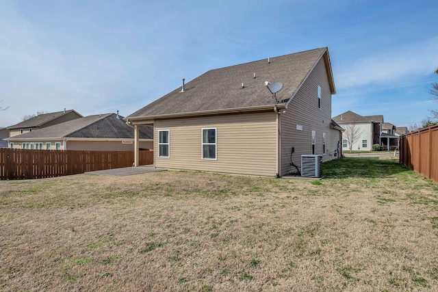 rear view of property featuring fence, central AC, and a yard