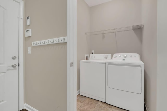 washroom with light tile patterned floors, laundry area, washing machine and dryer, and baseboards