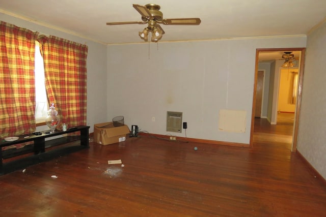 empty room featuring heating unit, ornamental molding, and dark wood finished floors