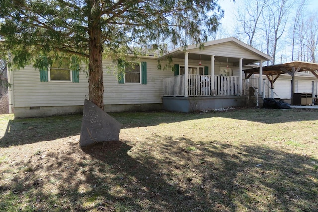 view of front facade with a porch, a detached carport, crawl space, and a front lawn