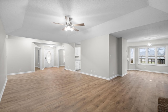 unfurnished living room with ceiling fan, baseboards, and wood finished floors