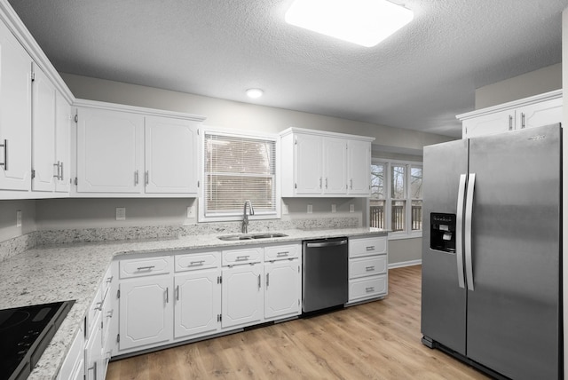 kitchen with white cabinets, light wood-style flooring, stainless steel appliances, and a sink