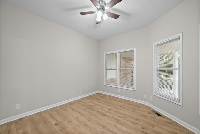 spare room featuring light wood-style floors, baseboards, visible vents, and a ceiling fan