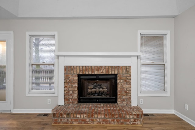 room details featuring a fireplace, wood finished floors, visible vents, and baseboards