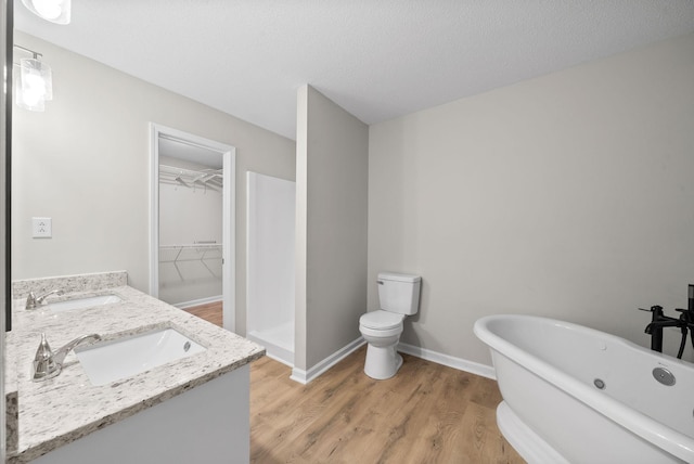 full bathroom featuring wood finished floors, a sink, baseboards, a soaking tub, and double vanity