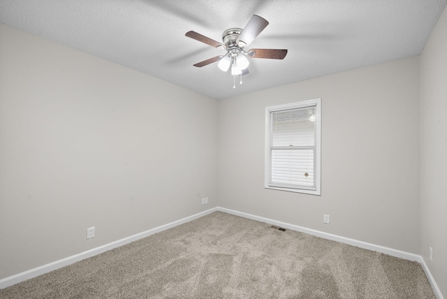 carpeted spare room with a ceiling fan, visible vents, baseboards, and a textured ceiling