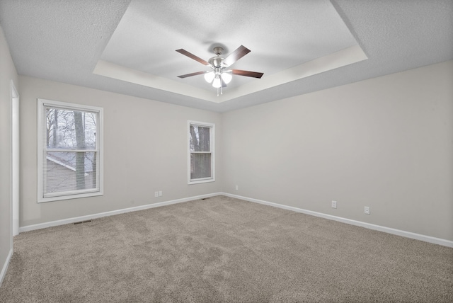 carpeted spare room featuring baseboards, a tray ceiling, ceiling fan, and a textured ceiling