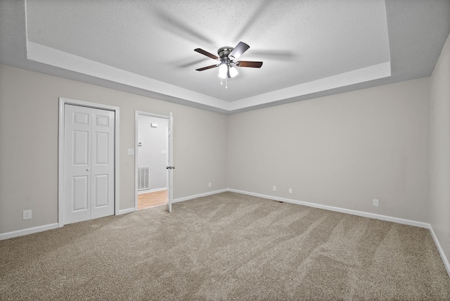 unfurnished bedroom with carpet floors, a raised ceiling, and visible vents