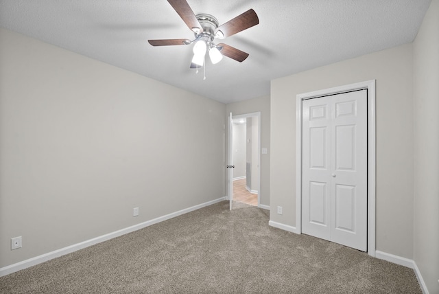 unfurnished bedroom featuring baseboards, a ceiling fan, a textured ceiling, carpet floors, and a closet