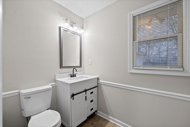 bathroom with toilet, a textured ceiling, vanity, baseboards, and tile patterned floors