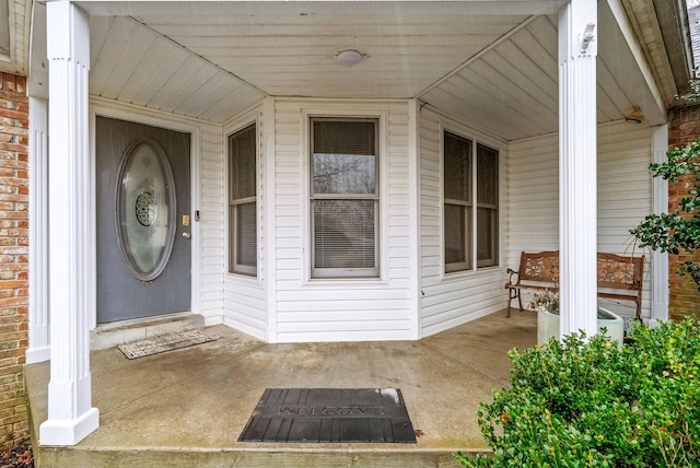 view of exterior entry with a porch and brick siding