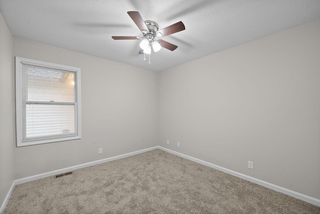 carpeted empty room with a ceiling fan, baseboards, visible vents, and a textured ceiling