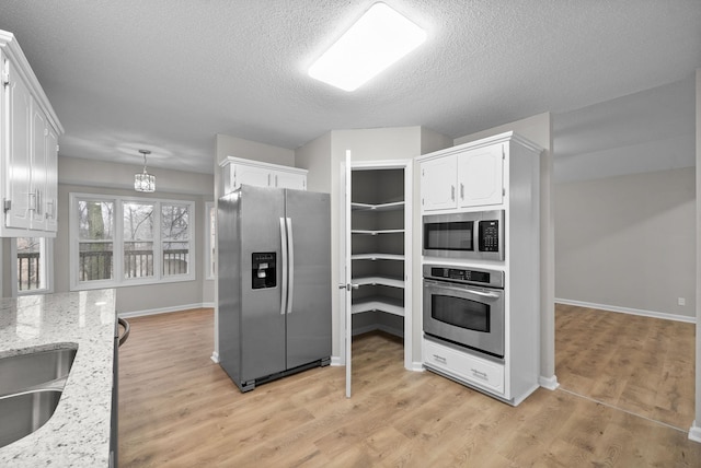 kitchen with light wood-type flooring, light stone countertops, white cabinetry, and stainless steel appliances