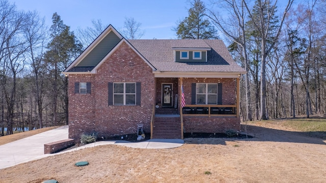 view of front of home featuring a porch, roof with shingles, and brick siding