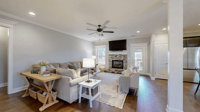 living area with a fireplace, a ceiling fan, baseboards, dark wood-style floors, and crown molding