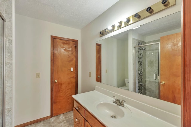 full bathroom with toilet, a stall shower, a textured ceiling, vanity, and baseboards