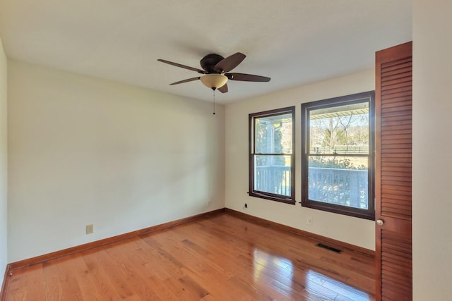 spare room featuring light wood-type flooring, baseboards, visible vents, and ceiling fan