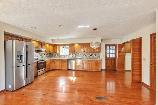 kitchen with pendant lighting, light countertops, visible vents, appliances with stainless steel finishes, and under cabinet range hood